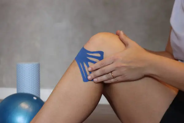 Dizine mavi kineziyoloji bandı yapıştıran kadın.