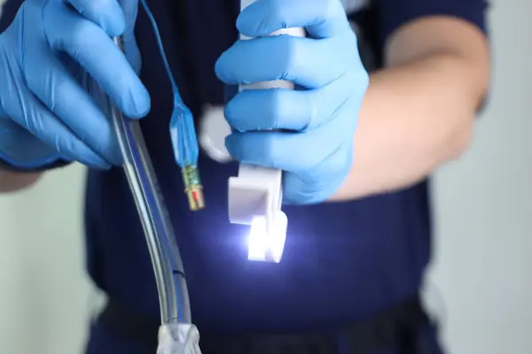 Elinde mavi eldivenli tıbbi cihaz tutan kişi.