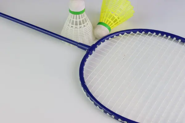 Badminton raketi ve beyaz üzerine iki mekik horozu.