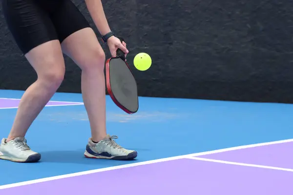 Mavi sahada Pickleball oynayan kişi