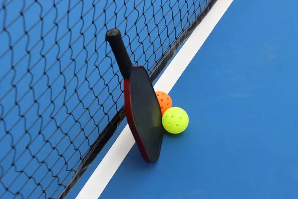 Pickleball raketi toplarla ağda dinleniyor.