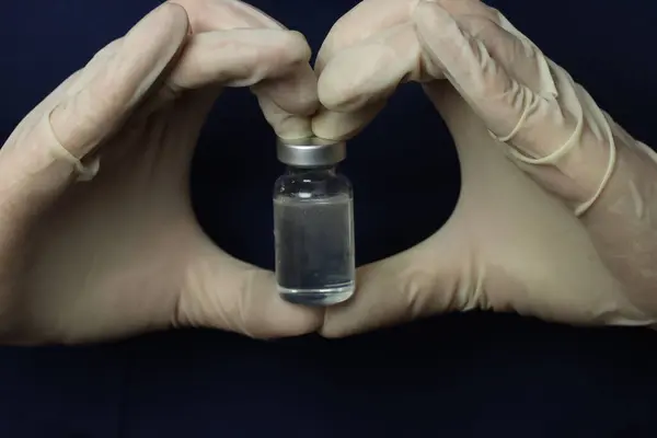 Eldivenli eller küçük şişeyi tutuyor