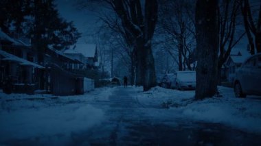 Kış akşamında kaldırıma yaklaşan kişi