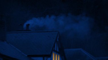 Sigara içilen baca ve gece ışıkları açık olan ev.