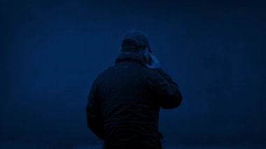 Adam geceleri dışarıda telefonla konuşuyor.