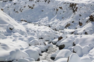 Himalaya 'daki nehir kıyısını ve taşları kar kapladı. Dünya haritasındaki uzun dağ sıraları ve parlak mücevherlerle noktalanmış Uttarakhand, şanlı tepe istasyonlarıyla ünlüdür..