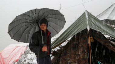 Himalaya eyaletinde şemsiyeli bir adam Uttarakhand Hindistan 'da. Himalaya eyaletlerinde havayı tahmin etmek imkansızdır. Himalaya bulutlarının güzelliği muazzam dağların üzerinde hareket ediyor..