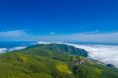 Geniş dağ manzarası, mavi güneşli gökyüzü ve Tenerife Adası, İspanya 'da aşağıda beyaz kabarık bulut denizi.