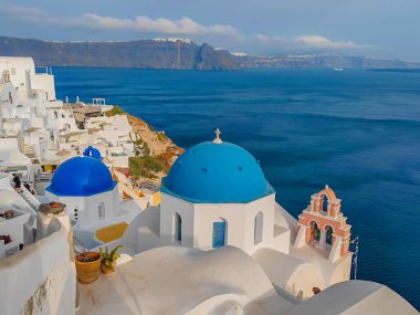 Santorini 'nin Oia kasabasındaki Agios Nikolaos Kilisesi' nin panoramik manzarası. Geleneksel ve ünlü beyaz evler ve Ege denizinde mavi kubbeleri olan kiliseler.