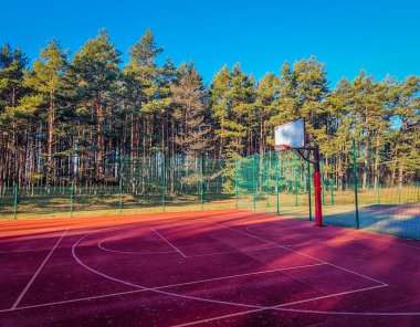 Ağaçlarla çevrili açık hava basketbol sahası.