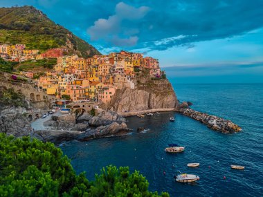 Günbatımında Cinque Terre 'de birçok renkli evi ve küçük tekneleri olan Manarola kasabasının hava panoramik manzarası.