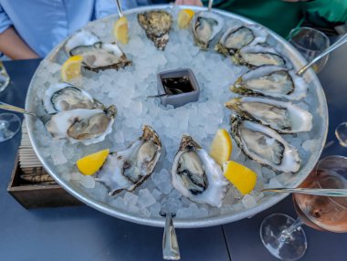 Müşterilere servis edilen bir restoranda servis edilen limonlu, buzlu ve soslu istiridye tabağı.