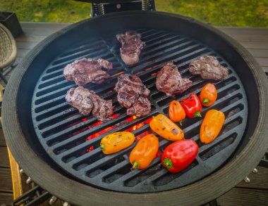 Oturma odasının terasında biftekli, fileminyonlu ve sebzeli bir barbekü ızgarası açık ateşte pişirilecek. 