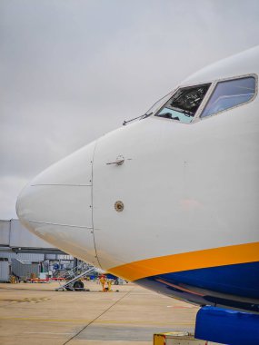 Havaalanı pistindeki bir otoparkta duran yolcu uçağı ve kokpitinin yan görüntüsü.. 