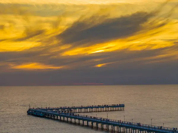 stock image Colorful sunset and Palanga resort pedestrian bridge, pier. Aerial drone photo of summer sunset horizon view over Baltic sea, Lithuania