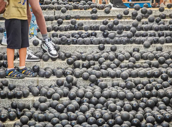 stock image 08 04 2024 - Kaunas, Lithuania. Hundreds or thousands of black rubber balls laying on the stone stairs in the city. Part of public street performance