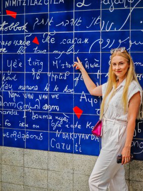 Montmartre Paris 'te aşk duvarında duran ve çeviriyi işaret eden genç bir kız. 