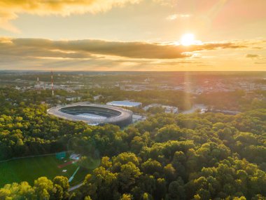 Kaunas Darius and Girenas football stadium, largest in Lithuania. Aerial view drone photo of a multi-use stadium in Azuolynas oak park during a sunset clipart