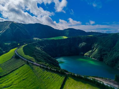 Fantastic scenic landscape with mountains and road to Lagoa de Santiago in Sao Miguel Island, Azores, Portugal. Aerial drone view of Acores islands clipart