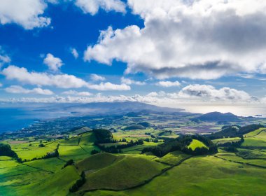 Portekiz 'deki Azores adalarında Sao Miguel' in insansız hava aracı görüntüsü. Dağlı manzara, yeşil çayırlar, mavi bulutlu gökyüzü ve okyanus. 