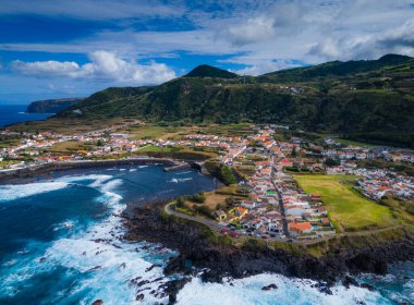 Mosteiros kasabası. Azores, Sao Miguel adasındaki köyün insansız hava aracı görüntüsü. Büyük turkuaz dalgalar ve dağlarla Atlantik Okyanusu kıyısında yer alıyor.