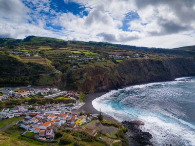 Mosteiros kasabası. Azores, Sao Miguel adasındaki köyün insansız hava aracı görüntüsü. Büyük turkuaz dalgalar ve dağlarla Atlantik Okyanusu kıyısında yer alıyor.