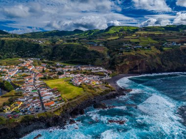 Mosteiros kasabası. Azores, Sao Miguel adasındaki köyün insansız hava aracı görüntüsü. Büyük turkuaz dalgalar ve dağlarla Atlantik Okyanusu kıyısında yer alıyor.