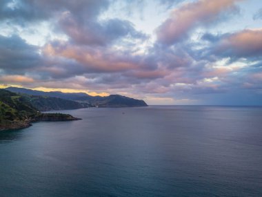 Azores adaları üzerinde gün batımını gösteren hava aracı görüntüsü. Ribeira Quente ve Praia do Fogo. Azores 'te yeşil dağları olan Sao Miguel kıyıları