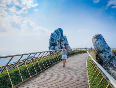 Güneşli bir günde Ba Na Hills, Vietnam 'da Altın Köprü' de poz veren güzel Avrupalı sarışın manken. Dağlardaki ikonik dünyaca ünlü köprü