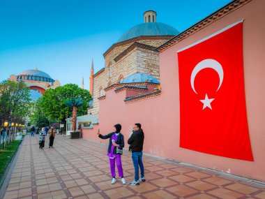 1229 2024 İstanbul, Türkiye. İstanbul 'un eski kentindeki kırmızı bir duvarda, dev Türk bayrağı önünde selfie çeken insanlar