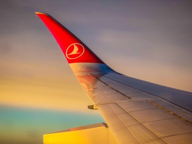 İstanbul, Türkiye - 01: 14 2025. Türk havayollarının uçak penceresinden bulutlara ve uçuş sırasında gün batımına bakış. Bulutların üstünde uçak kanadı. 