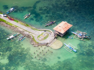 Filipinler 'in Bohol Adası, Panglao' daki Dauis kasabasında geleneksel Filipinli tekne iskelesi. Limandaki geleneksel Filipinli teknelerin insansız hava aracı görüntüsü