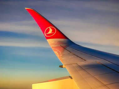 İstanbul, Türkiye - 01: 14 2025. Türk havayollarının uçak penceresinden bulutlara ve uçuş sırasında gün batımına bakış. Bulutların üstünde uçak kanadı. 