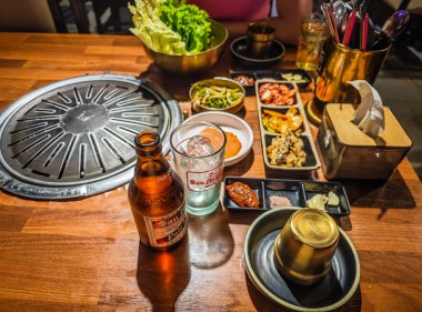 05 05 2025 - Bohol, Filipinler. Kore barbekü tarzı restoran. İçinde ızgara olan geleneksel Kore yemek masası. Domuz eti ve sığır eti kömür ocağında ızgaraya hazır.