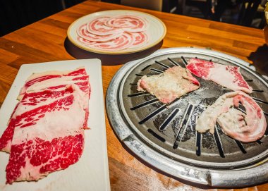 Kore barbekü tarzı restoran. İçinde ızgara olan geleneksel Kore yemek masası. Domuz eti ve sığır eti kömür ocağında ızgaraya hazır.