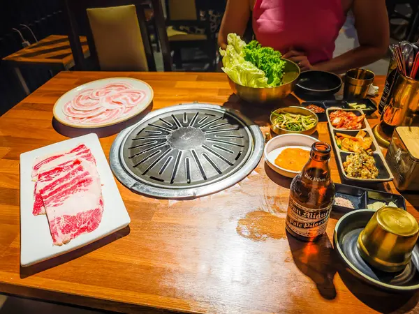 05 05 2025 - Bohol, Filipinler. Kore barbekü tarzı restoran. İçinde ızgara olan geleneksel Kore yemek masası. Domuz eti ve sığır eti kömür ocağında ızgaraya hazır.