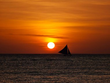 Boracay adası gün batımı manzaralı ve ufukta yelkenli var. Filipinler 'in deniz sularında altın bir saat boyunca inanılmaz günbatımı