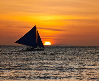 Boracay adası gün batımı manzaralı ve ufukta yelkenli var. Filipinler 'in deniz sularında altın bir saat boyunca inanılmaz günbatımı