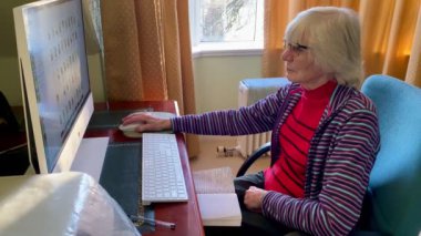 İngiltere 'ye e-posta göndermek için bilgisayar kullanan yaşlı bir kadın.