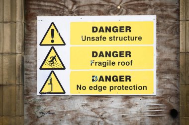 Unstable building keep out dangerous sign on fence at building construction site UK