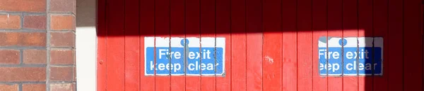 Fire exit keep clear sign on construction building site door UK