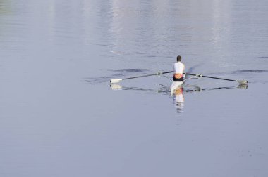 Adam sabahın erken saatlerinde İngiltere nehrinde kürek çekmek için kanoda antrenman yapıyor.