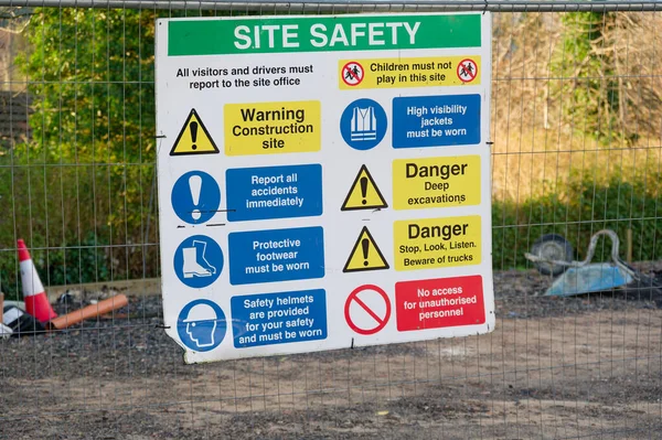 Construction site health and safety message rules sign board signage on fence boundary UK