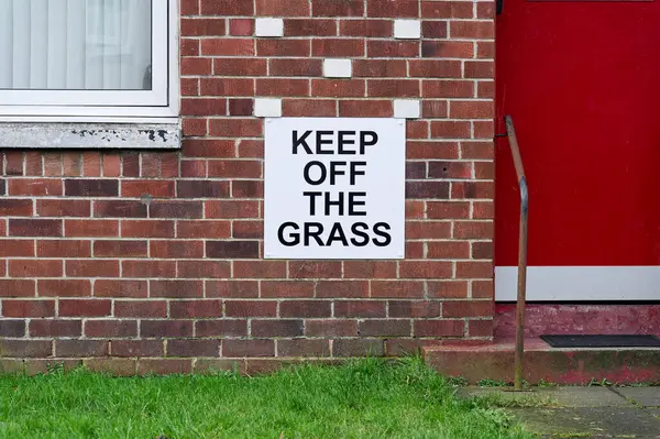 Keep off the grass sign on garden wall UK