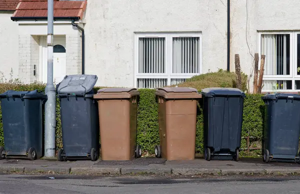 Wheelie bins in row for refuge collection outside council residential building UK