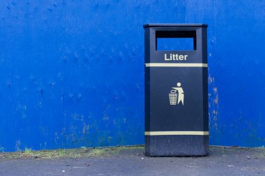 Glasgow İngiltere 'de mavi duvara karşı siyah çöp kovası.