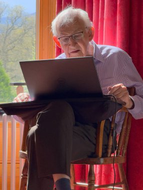Yaşlı bir adam siber saldırı ve online banka dolandırıcılığı riski altında dizüstü bilgisayar kullanıyor.