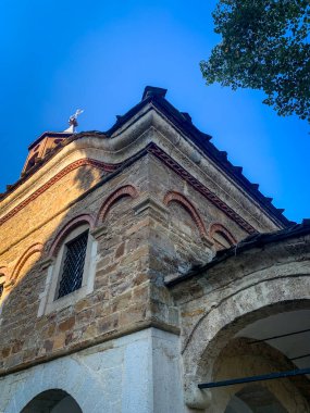 Bulgaristan 'ın Dryanovo kentindeki Aziz Nikola Kilisesi cephesinde, kemerli pencereleri ve çatısında bir haçı olan ayırt edici taş ve tuğla mimarisi yer alıyor..