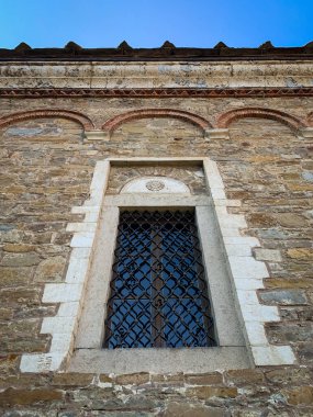 Bulgaristan 'ın Dryanovo kentindeki Saint Nikola kilisesindeki bir pencerenin süslü taş işçiliği ve hassas demir ızgarası, parlak mavi gökyüzünün arka planına karşı büyüleyici bir mimari ayrıntı oluşturuyor.