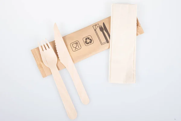 木製食器白い背景に隔離されたリサイクル可能なパッケージ上の木製フォークナイフとリサイクルナプキン — ストック写真